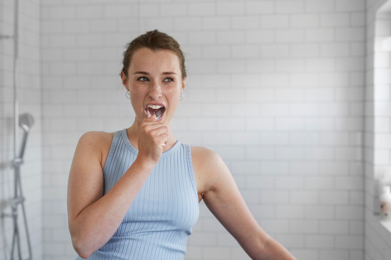 Tjej står i ett badrum och borstar tänderna.