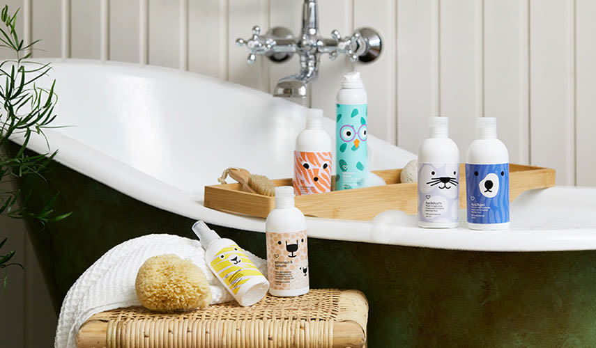 Vid ett badkar står hår- och hudvårdsprodukter från Apotek Hjärtats barnserie uppradade.