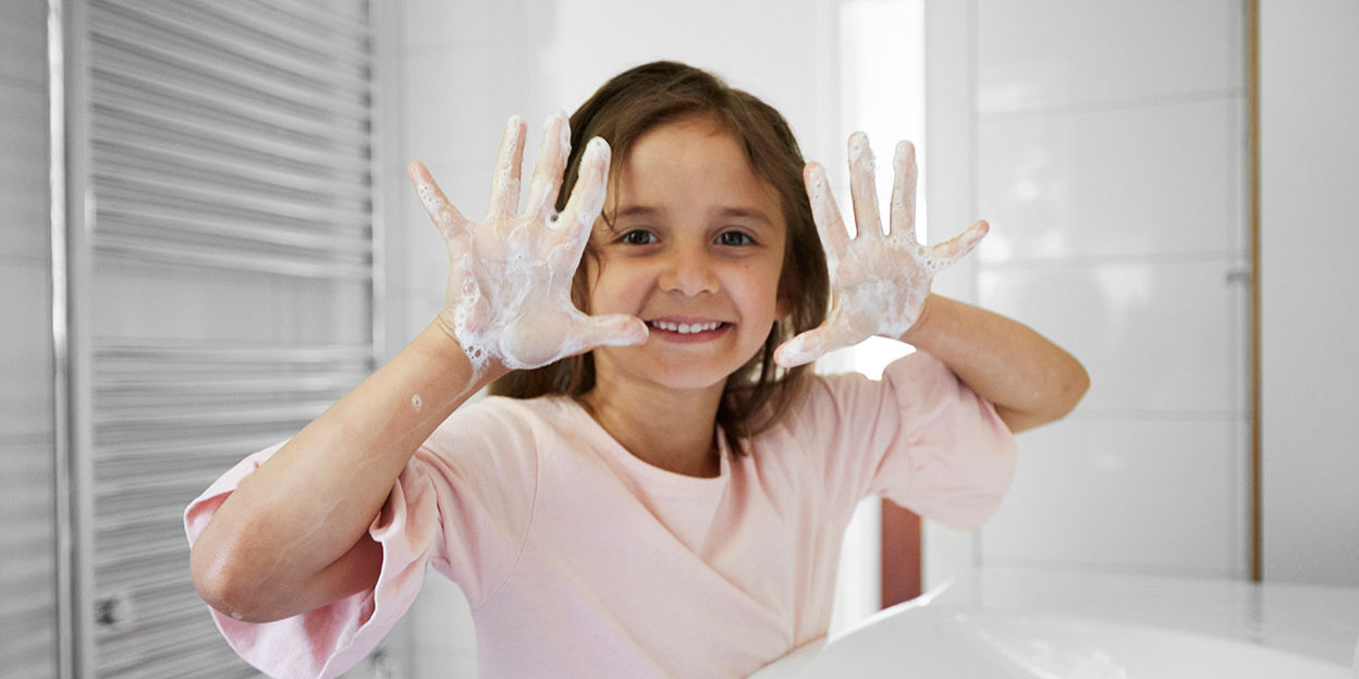Barn håller upp sina händer som har tvål på sig. 