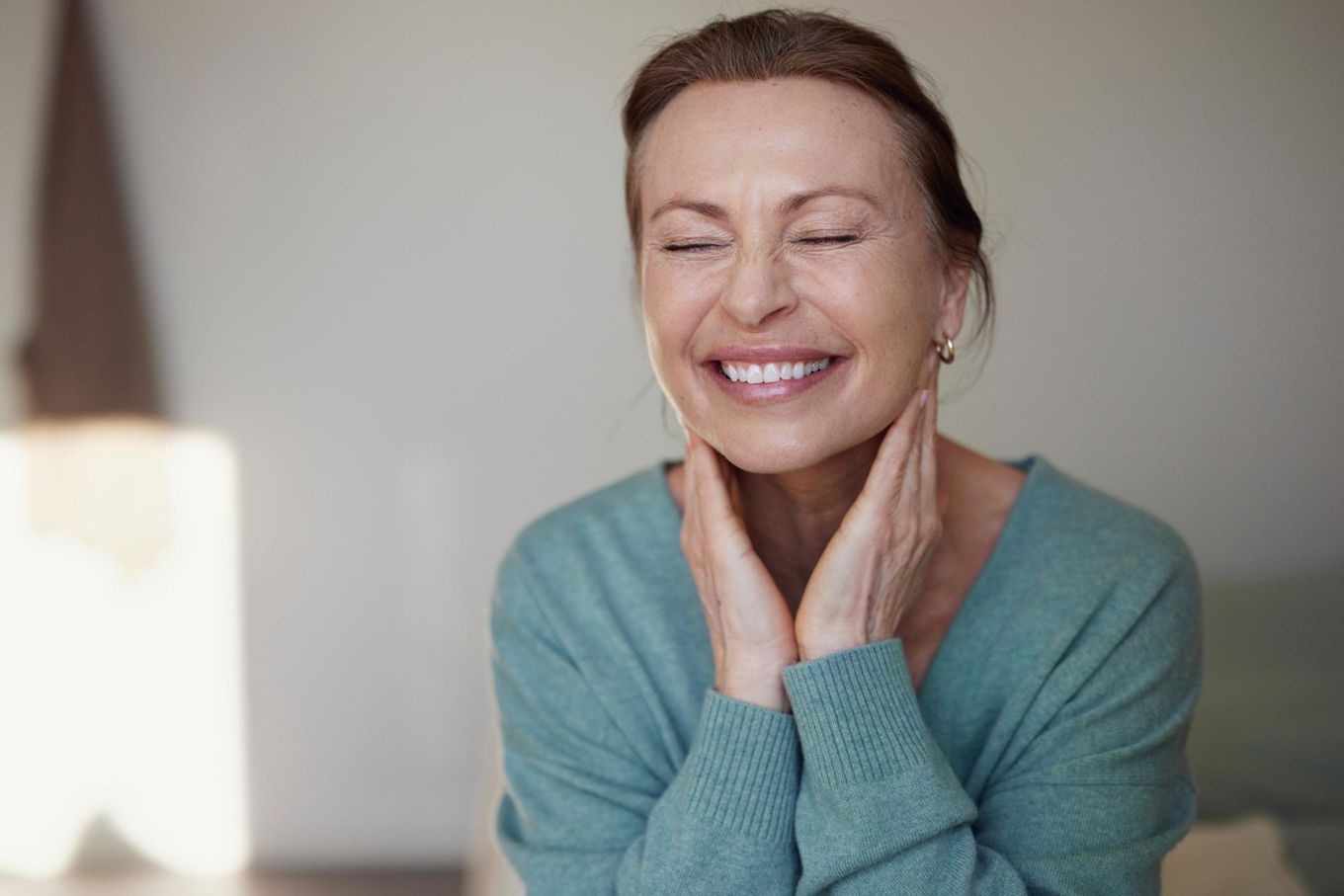 Kvinna blundar och ler, hon håller sina händer mot sin käke.